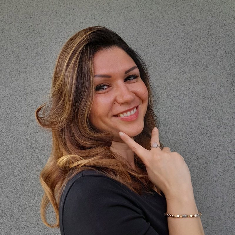 Andreea Maria Vieru titolare di AMV Consulenza, con abito nero su sfondo grigio
